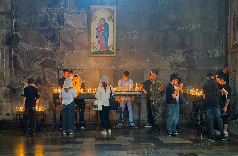 People gather in a church praying, surrounded by burning candles and murals, in a thoughtful mood, Tatev monastery, Armenian Apostolic monastery, Syunik province, Caucasus, Armenia