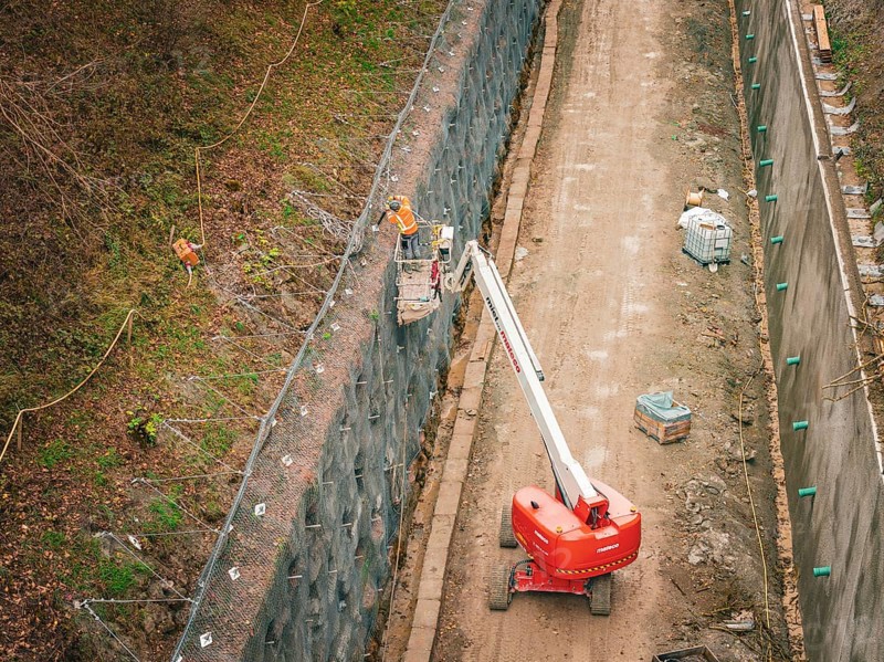 Construction workers on a lift attach a net to a steep slope, construction of the Hermann Hesse Railway, Im Hau, Calw, Germany