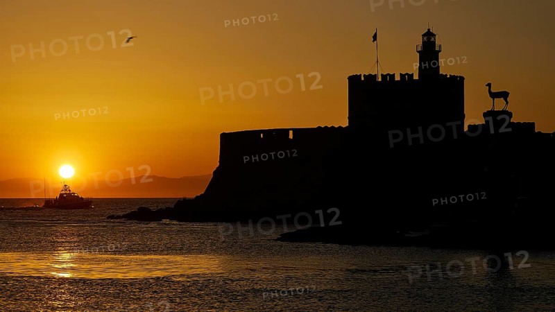 Agios Nikolaos fortress, sunrise over the sea with a castle silhouette and a passing boat, UNESCO World Heritage Site, Old Town of Rhodes Town, Rhodes, Dodecanese, Greece