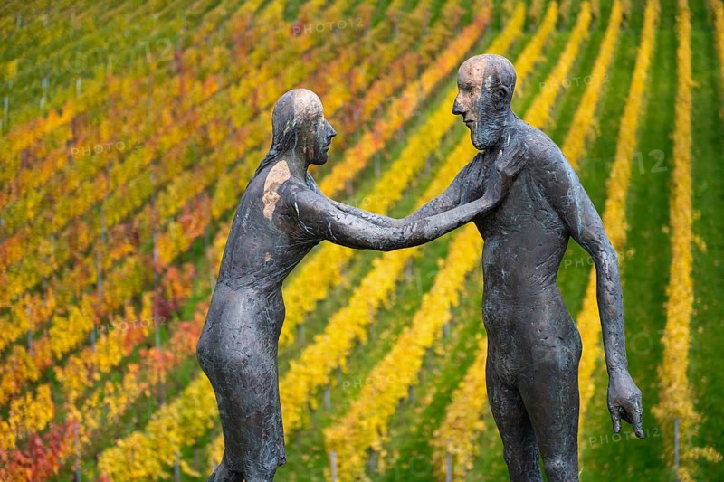 Sculpture of two people in front of colorful vines in autumn, emphasized by artistic expressiveness, sculpture trail near Strümpfelbach im Remstal, Baden-Württemberg, Germany