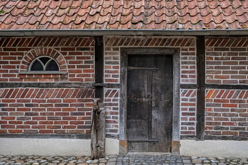 Wooden door in a traditional brick frame wall with roof tiles, Münsterland, North Rhine-Westphalia, Germany