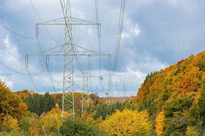 Power pylons against autumn-colored forest and cloudy sky, beech, mixed forest, Swabian Alb biosphere area, Baden-Württemberg, Germany