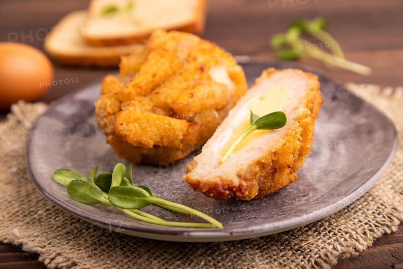 Chicken Schnitzel on gray plate with microgreen on brown wooden background and linen textile. side view, close up, selective focus