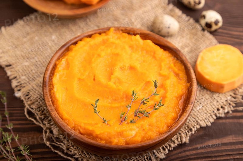 Sweet potato porridge in wooden bowl on wooden background and linen textile. Diet, healthy eating concept. side view, close up, minimalism, selective focus