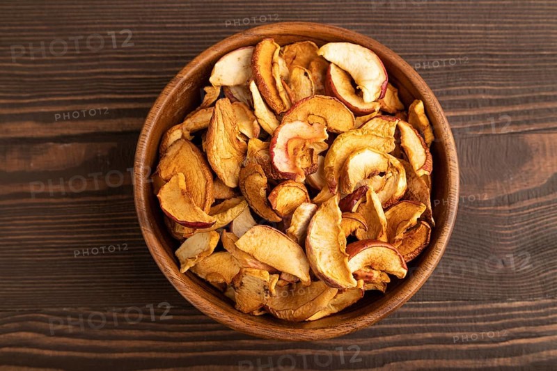 Dried Apples in wooden bowl on brown wooden background. Top view, close up, flat lay. healthy food, minimalism. sweet