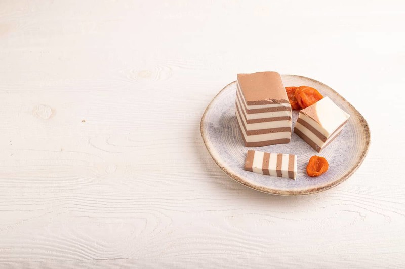 Cocoa and milk jelly with dried apricots on white wooden background, side view, copy space, minimalism