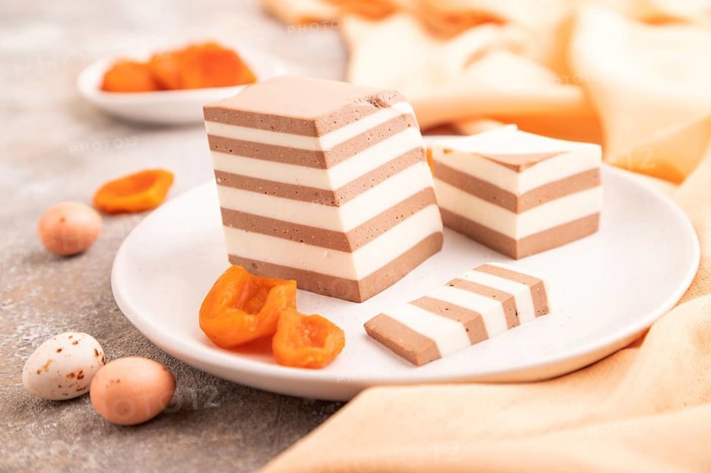 Cocoa and milk jelly with dried apricots on brown concrete background and orange textile, side view, close up, selective focus, minimalism
