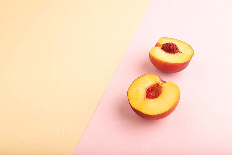 Peach Cut in half on orange and pink paper pastel background. Side view, copy space. healthy food, minimalism
