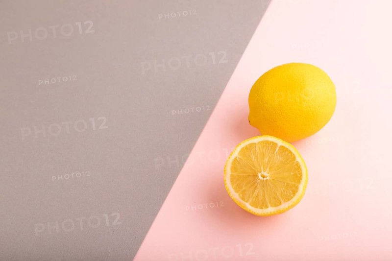 Yellow Lemon Cut in half on gray and pink pastel paper background. Side view, copy space. healthy food, vegetable, minimalism
