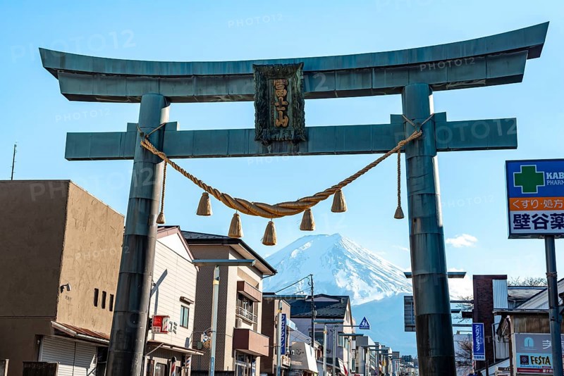 Large torii gate on above a street, street scene, in the back volcano Mt. Fuji, Fujiyoshida, Yamanashi Prefecture, Japan