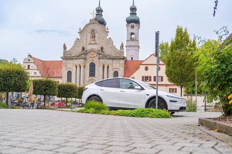 A modern car is parked in front of a historic church in the city center, ZFP Zwiefalten, Reutlingen district, Germany