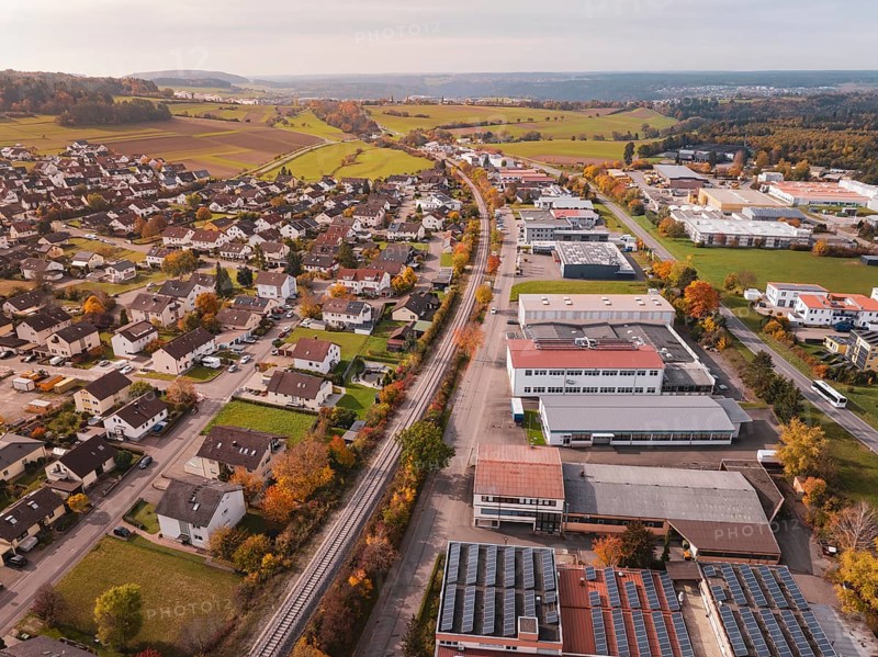 An urban landscape in autumn with a Hermann Hesse Bahn railway line surrounded by houses and industrial buildings, Althengstett, Calw district, Germany
