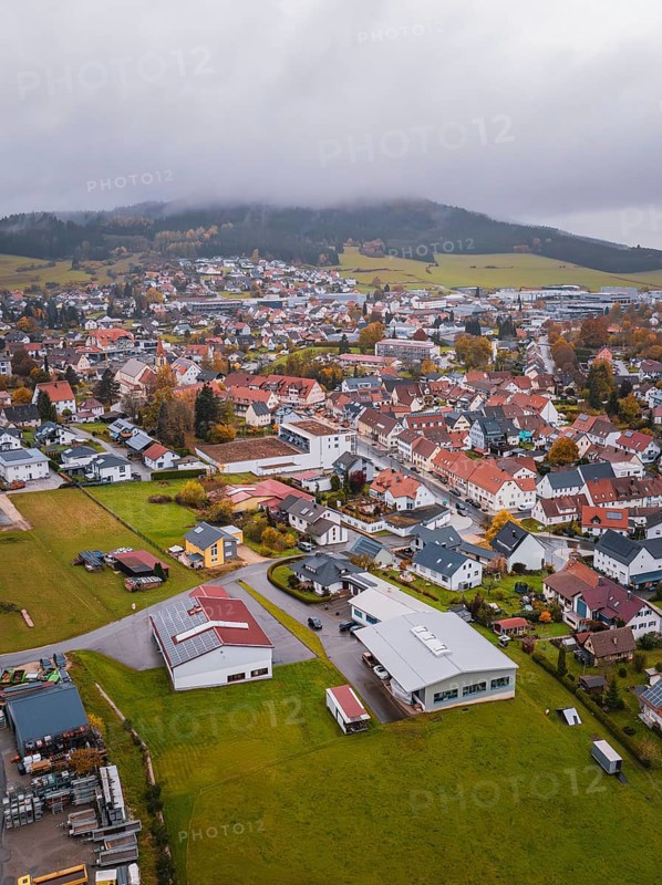 Small town with red roofs surrounded by fields and wooded hills under cloudy sky, Wehingen, Tuttlingen district, Germany