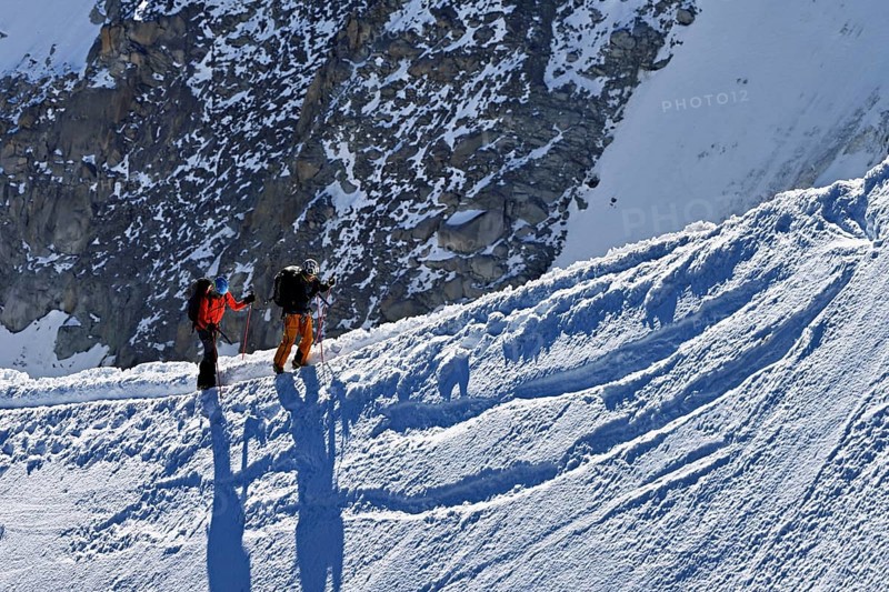 Two mountaineers run across a snow-covered mountain ridge, Aiguille du Midi, Chamonix-Mont-Blanc, Haute-Savoie, France
