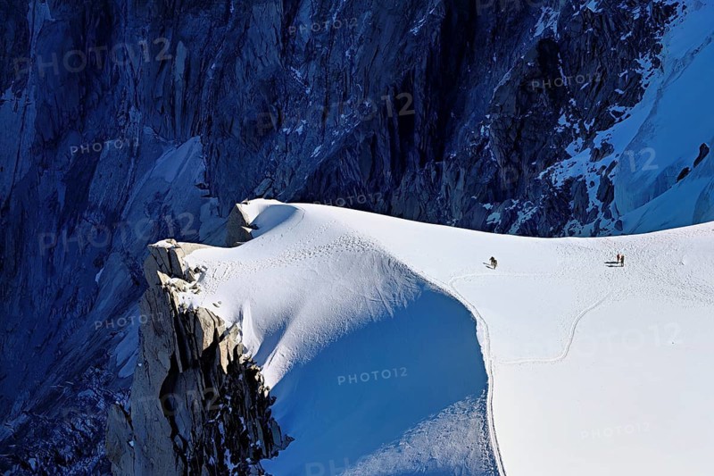 A group of mountaineers runs across a snow-covered mountain, Aiguille du Midi, Chamonix-Mont-Blanc, Haute-Savoie, France