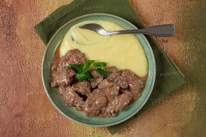 Liver beef stroganoff with mashed potatoes, table setting in green tones, homemade