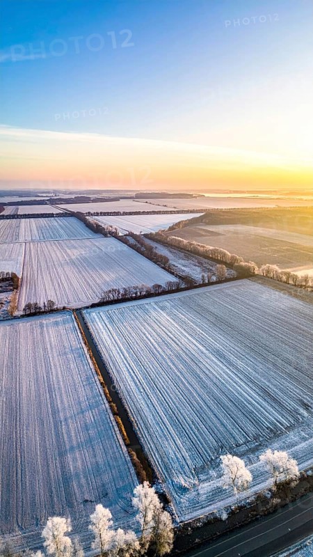 Bird Eye Perspective of Frost Covered Farmland. Seasonal Agricultural Scenery, winter and autumn scene, blue sky with golden light at sunrise, AI generated