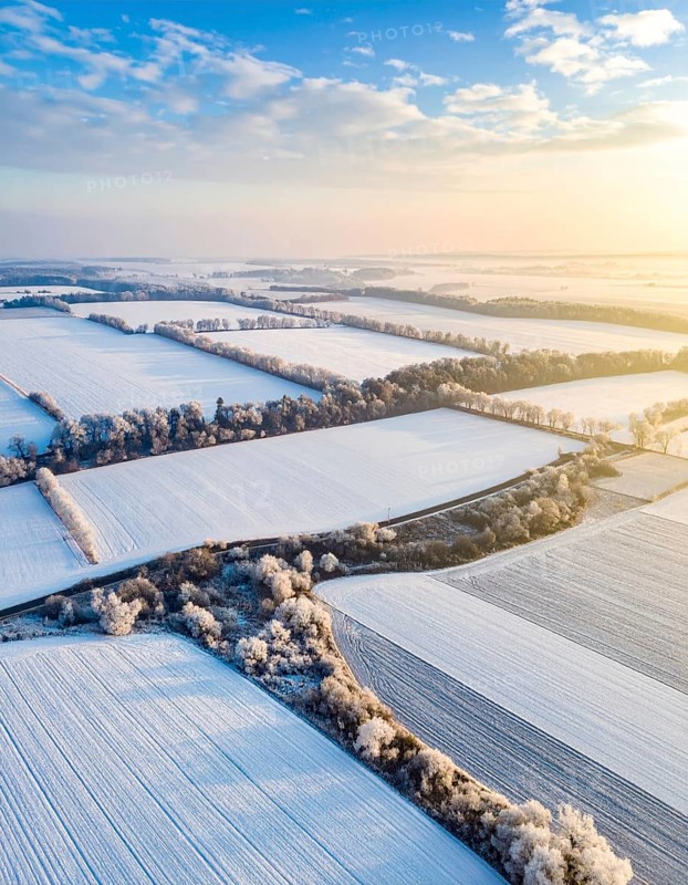 Bird Eye Perspective of Frost Covered Farmland. Seasonal Agricultural Scenery, winter and autumn scene, blue sky with golden light at sunrise, AI generated