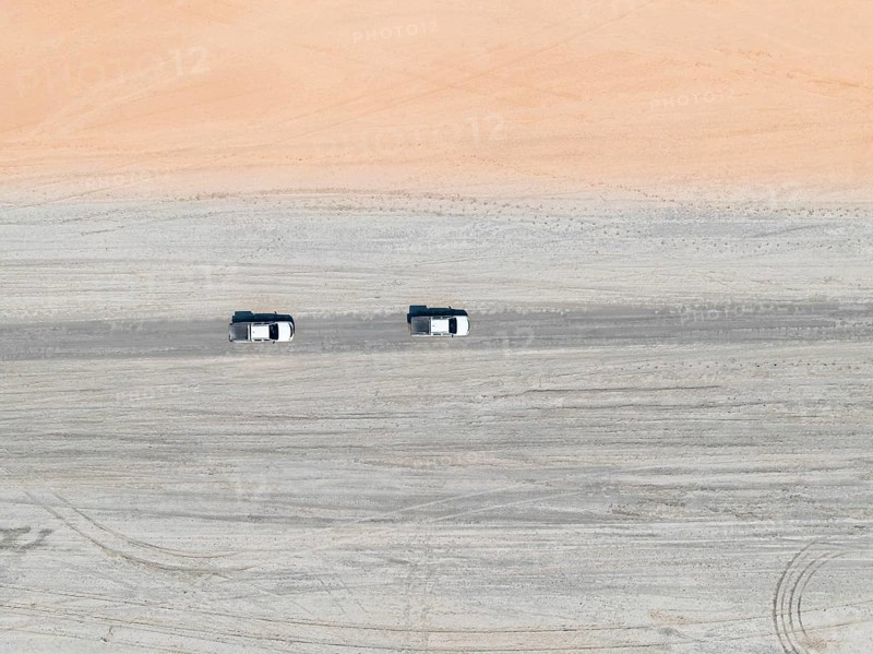 Aerial view, top-down view, two off-road cars driving on a road in arid countryside, Botswana