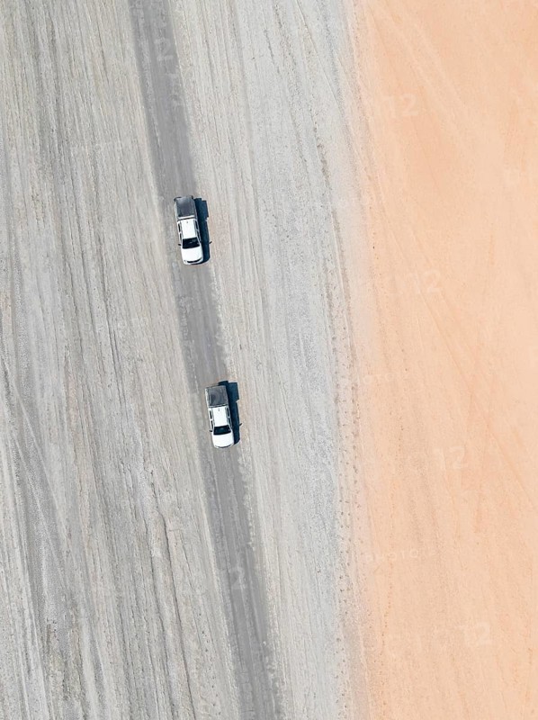 Aerial view, top-down view, two off-road cars driving on a road in arid countryside, Botswana