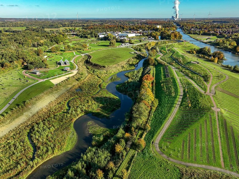 Castrop-Rauxel, North Rhine-Westphalia, Germany - Autumn on the restored Emscher, EMSCHERLAND adventure park, a new nature and water adventure park on the restored Emscher, at the Emscher water cross with the Rhine-Herne Canal on the city limits of Recklinghausen and Castrop-Rauxel. A new vineyard in front. Flood protection through area expansion. The ecological focus at the confluence of the Suderwicher Bach and Emscher rivers will also be a future garden of the IGA 2027 International Garden Exhibition. Before the restoration, the river system of the Emscher was an open, aboveground waste water channel, mixed water channel with surface water and waste water. Back right, the new bridge jump over the Emscher. On the horizon the Datteln 4 power plant