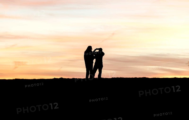 Walkers with mobile phone at sunset on a dike, Fehmarn island, 13.10.2025, Fehmarn, Schleswig-Holstein, Germany