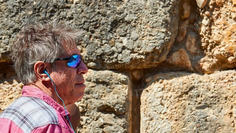 Visitor wearing sunglasses stands in front of the huge stone walls of the Lion Gate, Archaeological Site, UNESCO World Heritage Site, Mycenae, Mycenae, important city in pre-classical times, Peloponnese, peninsula, Greece