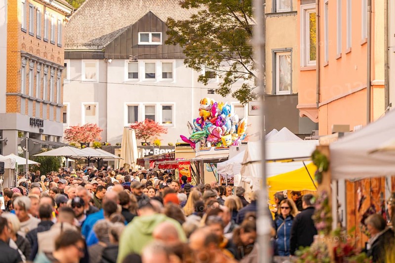 Busy shopping street in autumn, people strolling between modern buildings and colorful shops, Urschelherbst street festival, Nagold, Germany