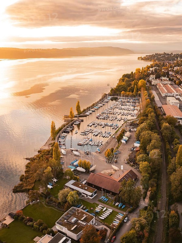 A harbor with anchored boats at sunset, surrounded by an urban landscape in autumn, Überlingen, Lake Constance, Germany
