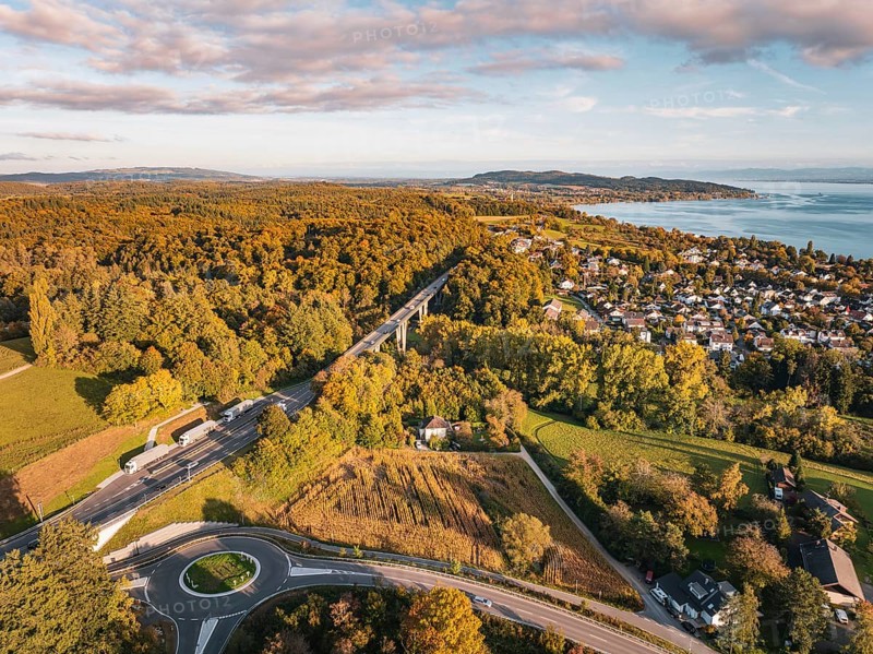 Highway through a forest, with a view of a nearby town and the lake on the horizon under clouds, Überlingen, Lake Constance, Germany