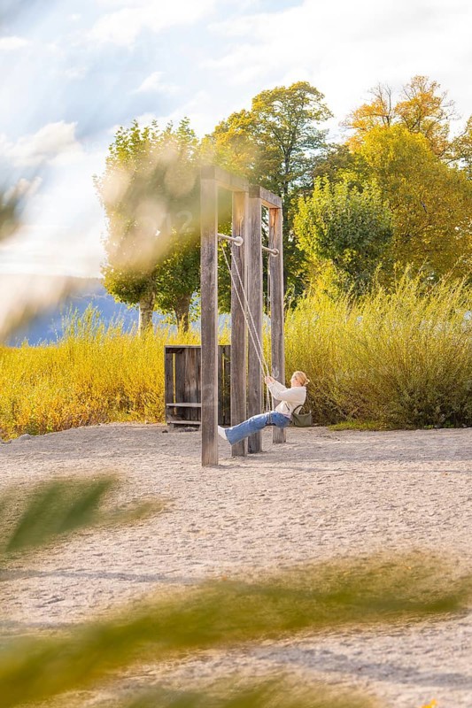 Child swings on a playground in autumn surrounded by colorful trees, Überlingen, Lake Constance, Germany