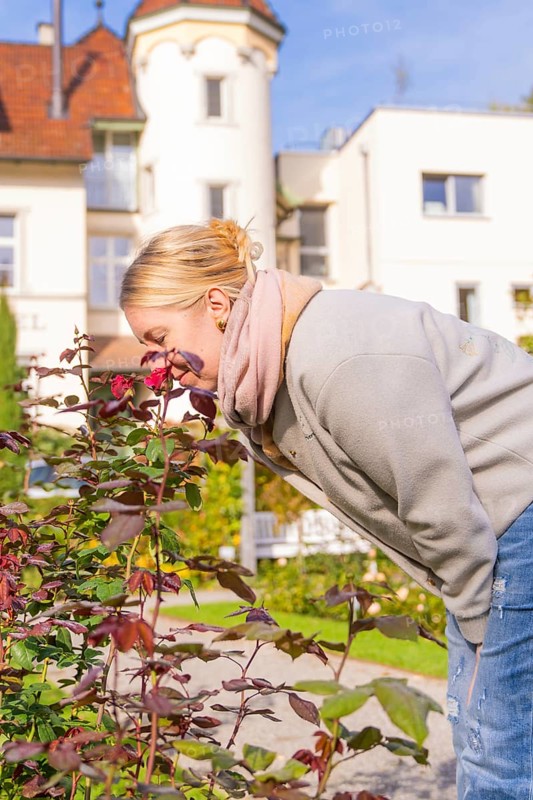 Woman with red hair enjoying the scent of flowers in autumn garden, Überlingen, Lake Constance, Germany