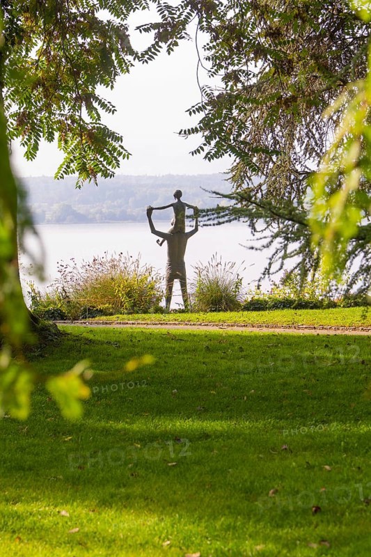 A statue in a park surrounded by trees and green grass with an autumnal atmosphere, Überlingen, Lake Constance, Germany
