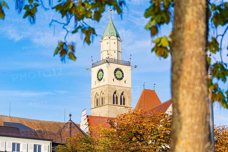 Church tower against blue sky with autumn leaves in the foreground, Überlingen, Lake Constance, Germany