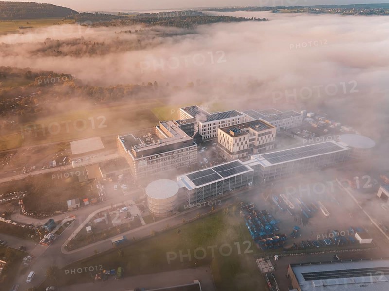 Bird's-eye view of industrial building group in mystical fog weather, new hospital health campus building, Calw, Germany