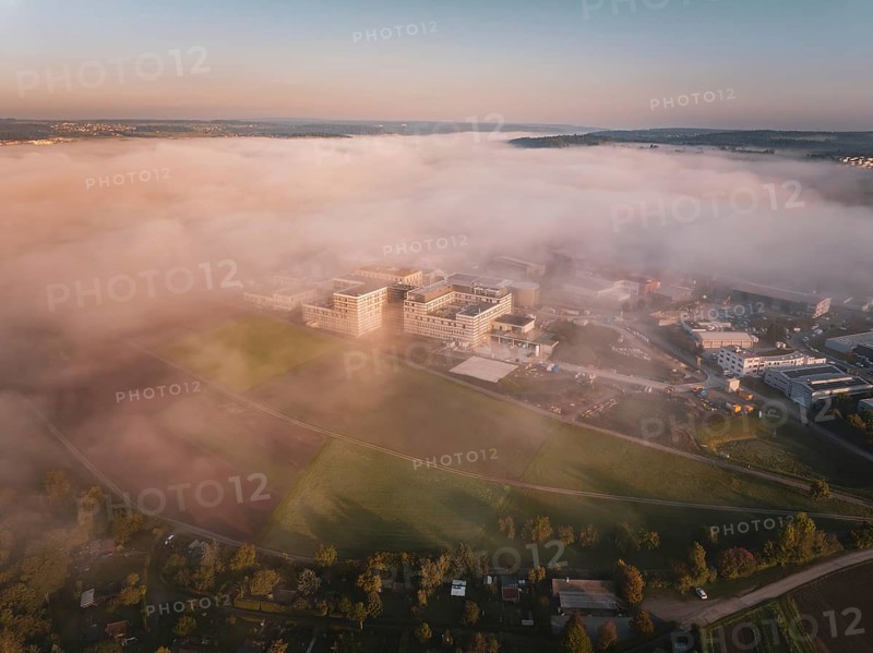 View of buildings in fog surrounded by landscape at the beginning of the day, new hospital health campus building, Calw, Germany