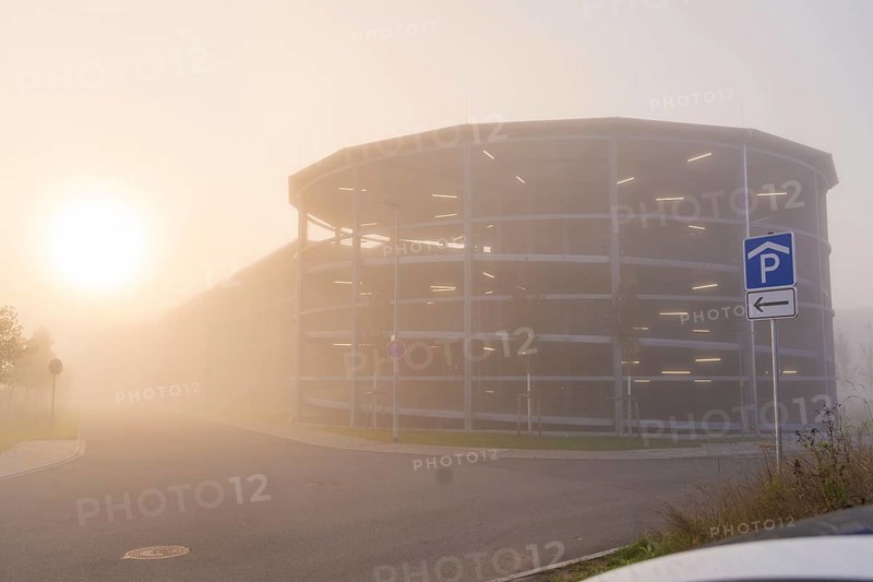 Misty street with parking garage at sunrise, mystical atmosphere, new hospital health campus building, Calw, Germany