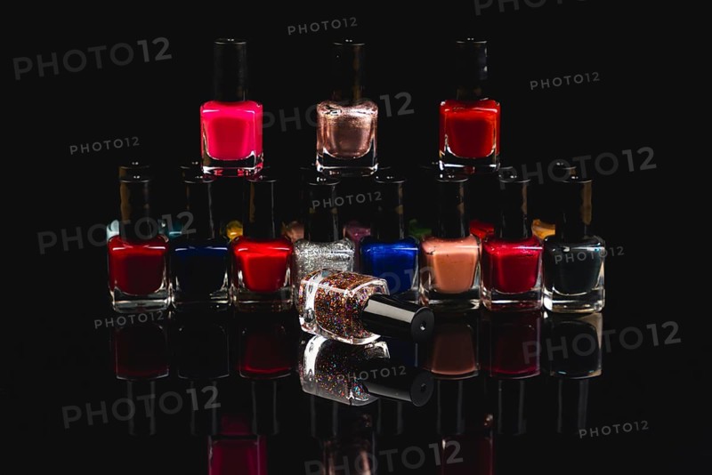 Colourful nail polish bottles with reflections against a black background