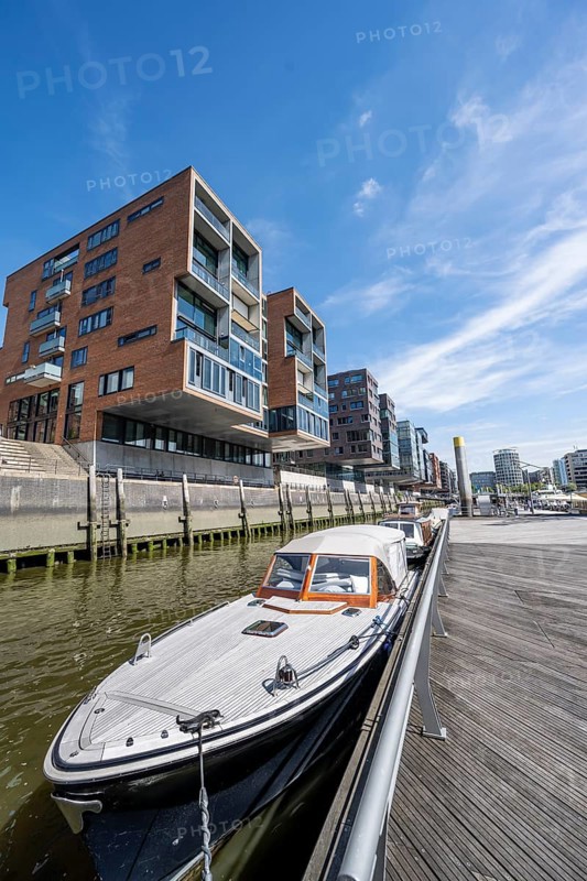 Modern residential buildings, boats at the traditional shipping harbor on Sandtorkai, behind Elbphilharmonie, HafenCity, Hamburg, Germany