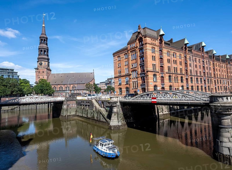 Boat on the Kleines Fleet canal with Kannengießer bridge and tower of the main church of St. Katharinen, Speicherstadt. Hamburg, Germany