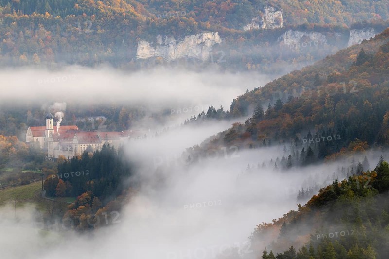View of Benedictine monastery Beuron, Archabbey of St. Martin, limestone rock, rock face, mixed forest, autumn colours, fog, autumn, Fridingen, Danube Valley, Upper Danube nature park Park, Baden-Württemberg, Germany