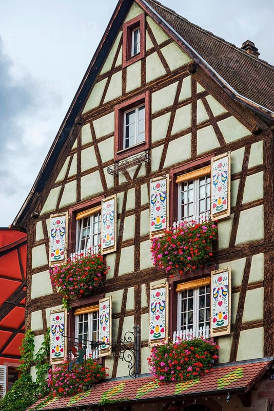 Decorated half-timbered house with ornate windows and flowers in the old town centre of Kaysersberg
