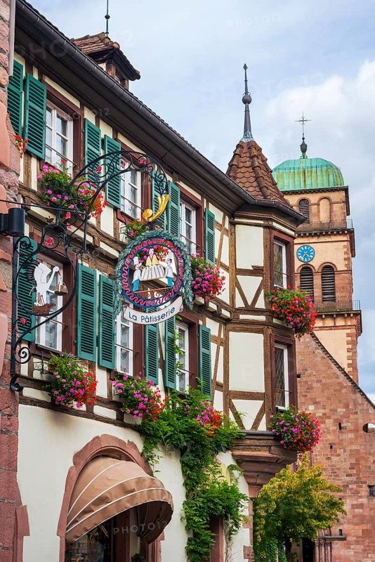 Decorated half-timbered house with guild sign of a patisserie in the old town centre of Kaysersberg