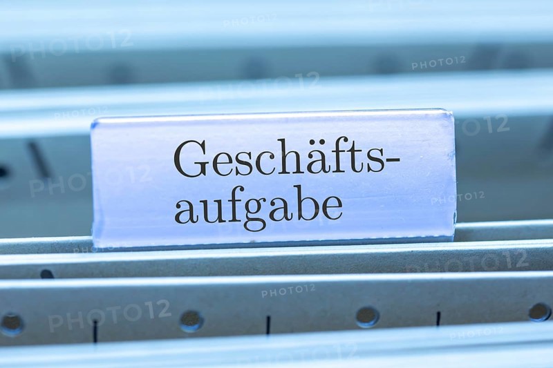 (Photomontage) Sign with the inscription GESCHÄFTSAUFGABE on a suspension file index