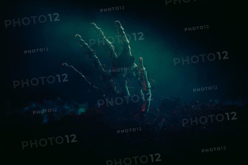 A single skeletonised hand protruding eerily from the dark earth, Halloween