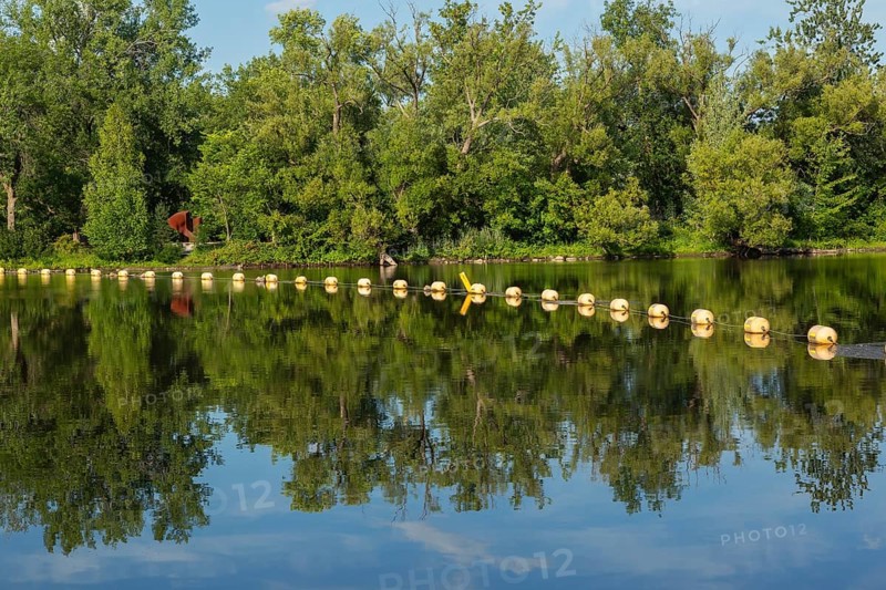 String of yellow cautionary navigation marker buoys on water surafce of river serving to warn, signal or indicate of a hazard beyond, Terrebonne, Quebec, Canada