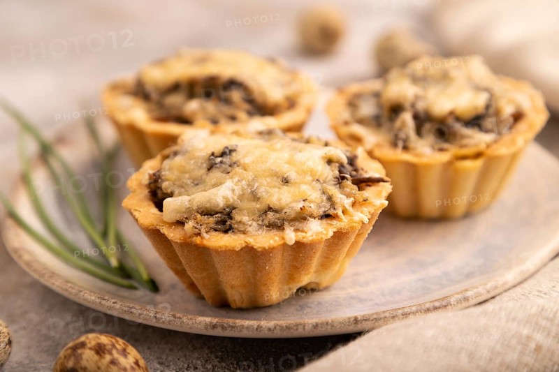 Tartlets with meat and cheese on brown concrete background and linen textile. side view, close up, selective focus