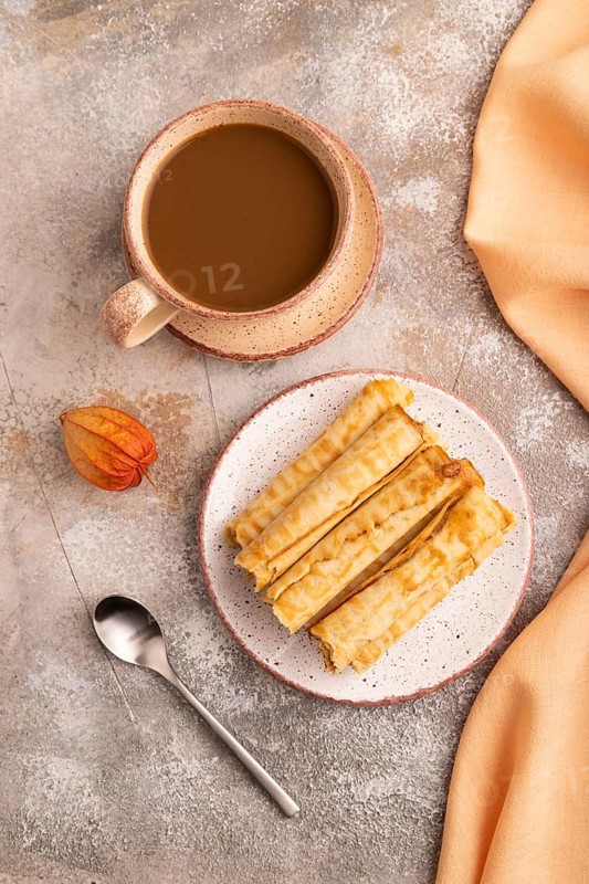 Waffles with caramel on brown concrete background and orange linen textile, cup of coffee, top view, flat lay, close up