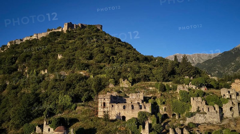 Drone image, Byzantine castle perched on a wooded hill under a blue sky, Mystras, Mistra, UNESCO World Heritage Site, Medieval Byzantine ruined city, northwest of Sparta, foothills of the Tyagetos Mountains, Peloponnese, peninsula, Greece