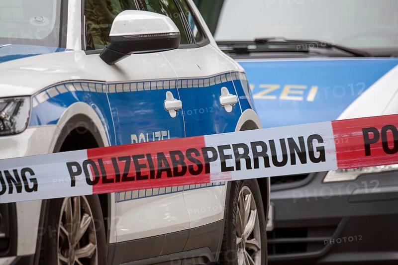 (Photomontage) Symbolic image of a police operation: police cordon in front of emergency vehicles